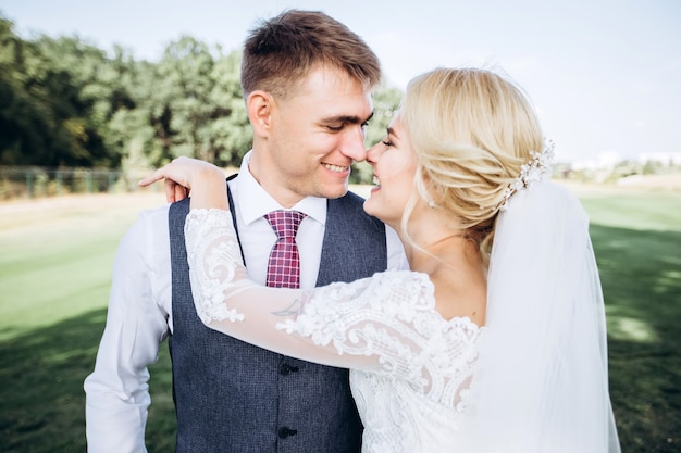 Bride and groom hugging, kissing outdoors on a wedding day, young couple, valentine's day