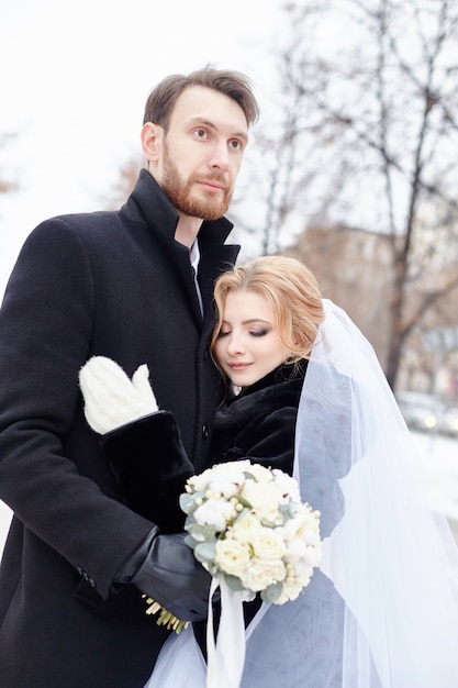 Bride and groom hugging and kissing in winter