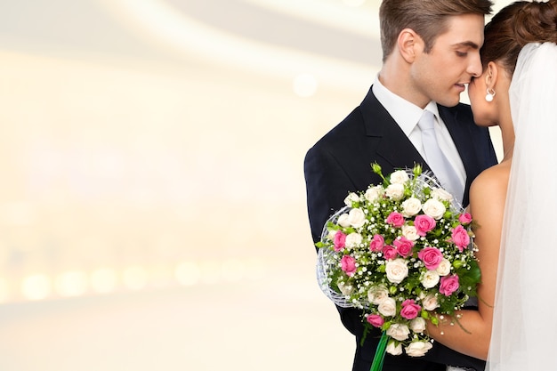 Bride and groom hugging on light background