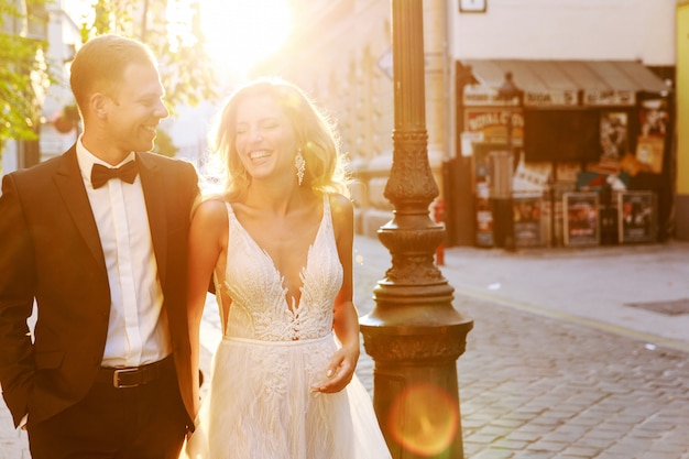 Bride and groom hugging in the old town street. Wedding couple in love. Luxury rhinestone dress.