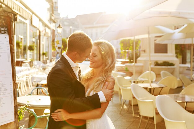 Bride and groom hugging in the old town street. Wedding couple in love. Luxury rhinestone dress.