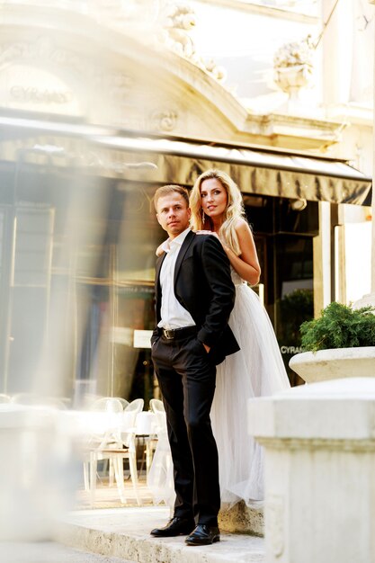 Bride and groom hugging in the old town street. Wedding couple in love. Luxury rhinestone dress.