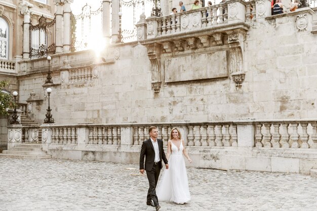 Bride and groom hugging in the old town street. Wedding couple in love. Luxury rhinestone dress.