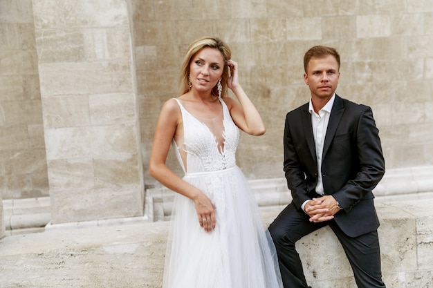 Bride and groom hugging in the old town street. Wedding couple in love. Luxury rhinestone dress.