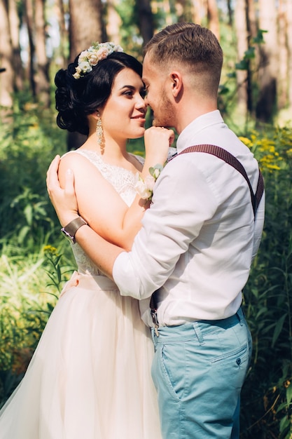 Bride and groom hugging on wedding day, happy young couple kissing in park in nature, valentine's day