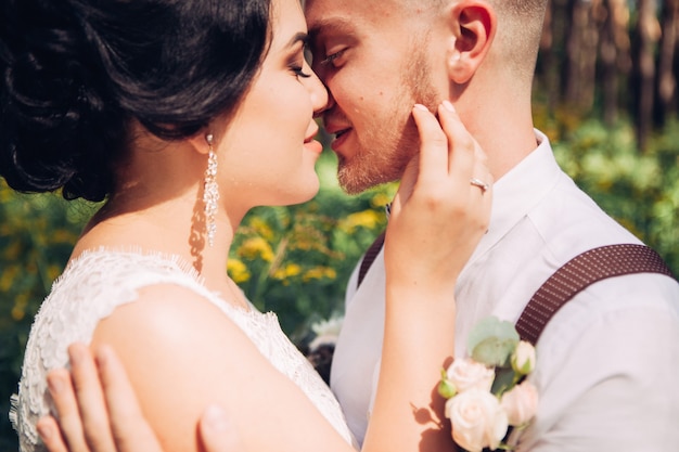 Bride and groom hugging on wedding day, happy young couple kissing in park in nature, valentine's day