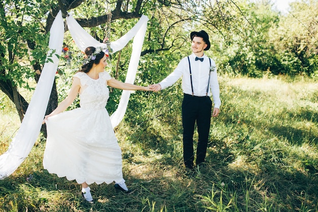 Bride and groom hugging on wedding day, happy young couple kissing in park in nature, valentine's day