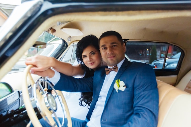 Foto sposa e sposo all'interno di un'auto classica. loro sono felici.