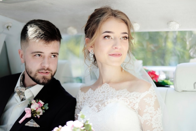 Sposa e sposo all'interno di un'auto di lusso