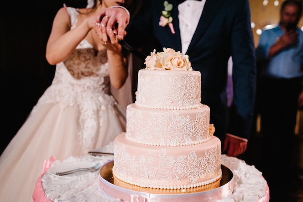 La sposa e lo sposo stanno tagliando la loro torta nuziale rustica sul banchetto di nozze sposi che mangiano la torta