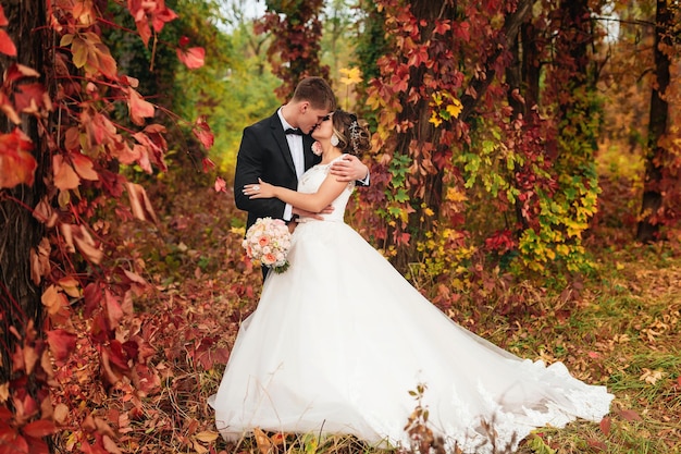 Bride and groom kissing in an autumn park