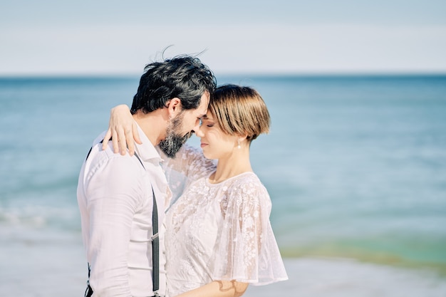 Жених и невеста целуются на пляже и радостно празднуют свадьбу