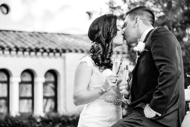 Foto la sposa e lo sposo si baciano mentre brindano allo champagne.