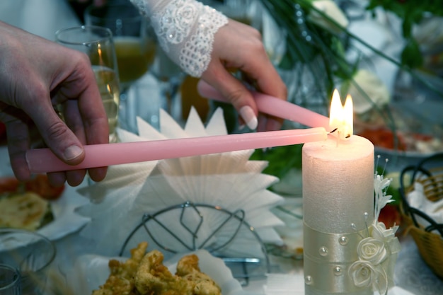 결혼식장에서 신랑 신부가 결혼식 초에 불을 붙이고 있다. 두 영혼의 통일