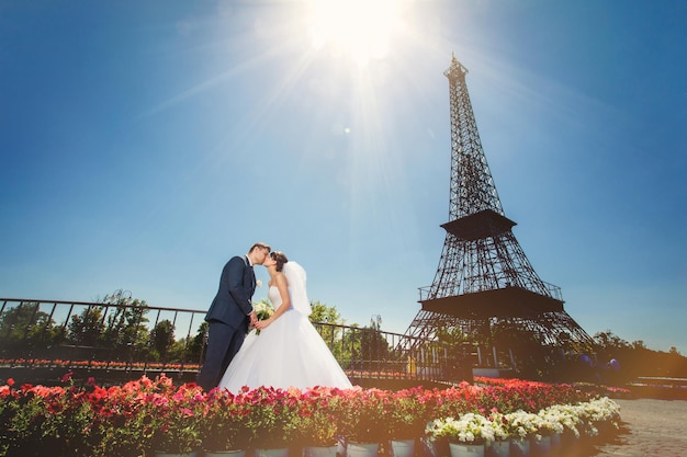 Bride and groom in modern summer park near copy of Eiffel Tower