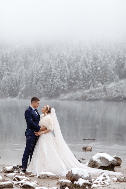 Bride and groom in mountain near the lake in winter