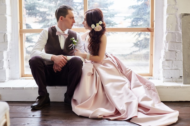 Bride and groom near big window hugging before wedding.