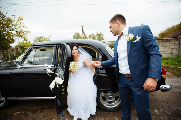 Sposa e sposo vicino all'automobile classica. loro sono felici