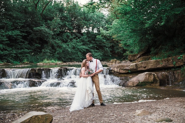 Sposa e sposo vicino al fiume di montagna