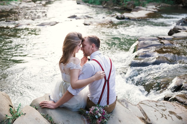 Sposa e sposo vicino al fiume di montagna