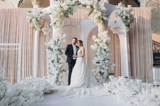 Photo bride and groom near wedding arch