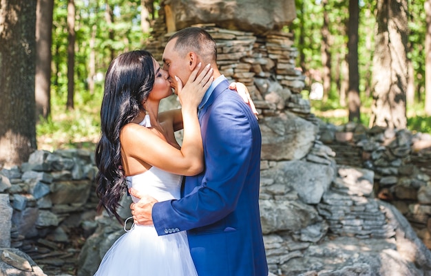 bride and groom in the park on a sunny day, couple in love kisses in nature