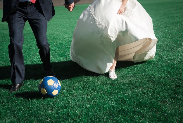 Photo the bride and groom play football on the football field wedding tradition legs of the bride and