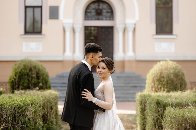 a bride and groom pose in front of a pink house