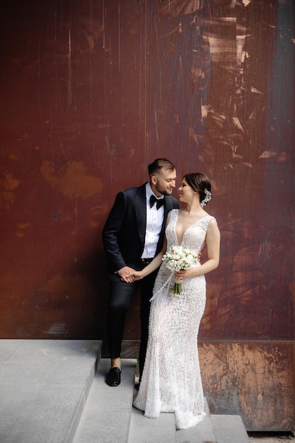 A bride and groom pose in front of a rust wall at the brooklyn botanic garden.