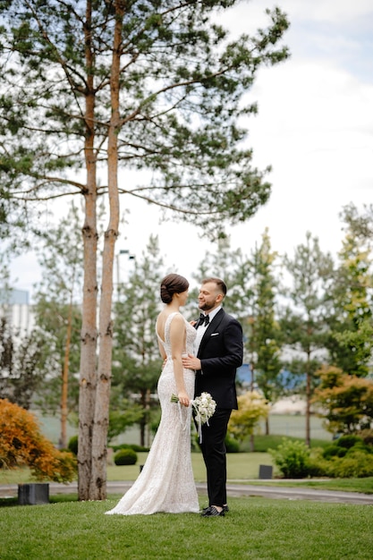 A bride and groom pose for a photo in front of trees.