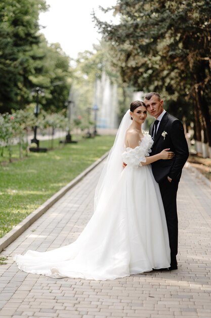 a bride and groom pose for a photo in a park