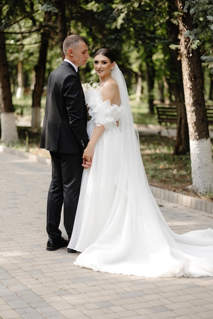 the bride and groom pose for a photo in a park