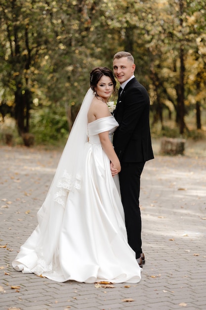 the bride and groom pose for a photo in the park