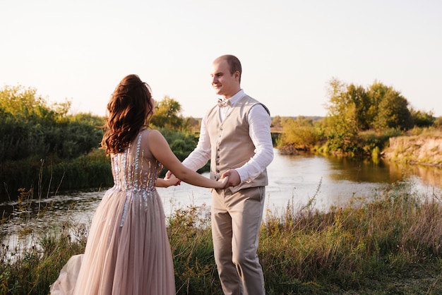 Bride and groom posing across the field near the river