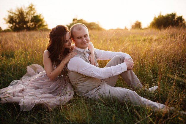 Bride and groom posing in the field at sunset