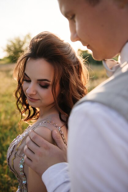 Bride and groom posing in the field at sunset