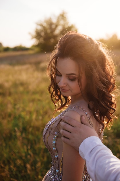 Foto sposa e sposo che posano nel campo al tramonto