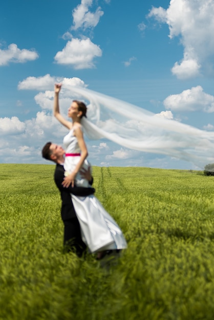 Жених и невеста позирует на зеленом поле