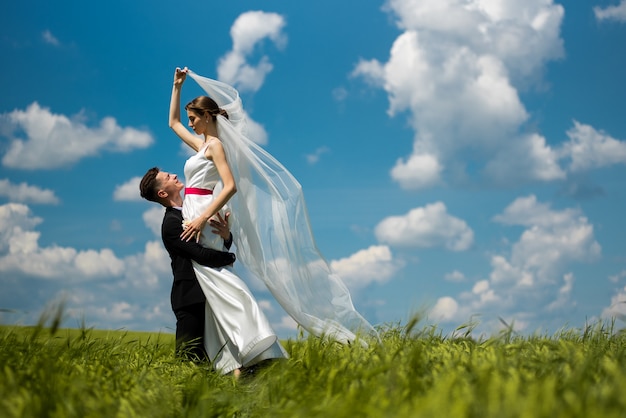 Bride and groom posing on green field