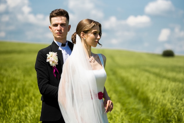 Bride and groom posing on green field