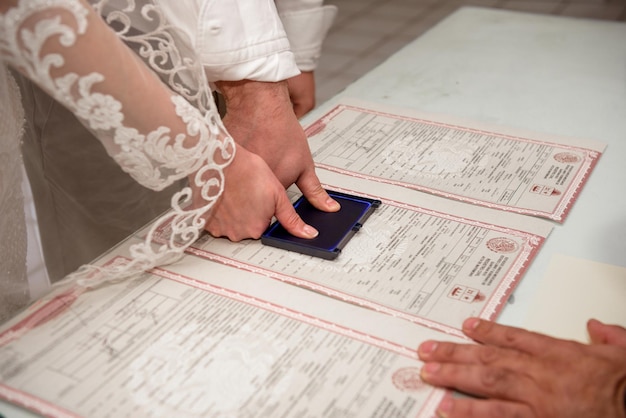 Foto la sposa e lo sposo hanno messo le impronte digitali sul certificato di matrimonio.