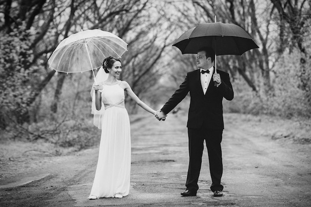 Bride and groom on a rainy wedding day walking under an umbrella