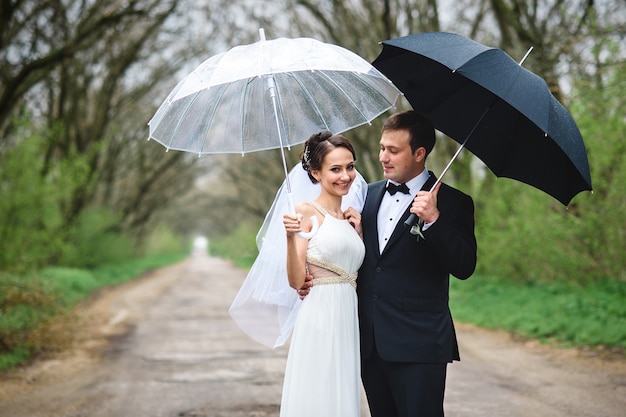 Bride and groom on a rainy wedding day walking under an umbrella