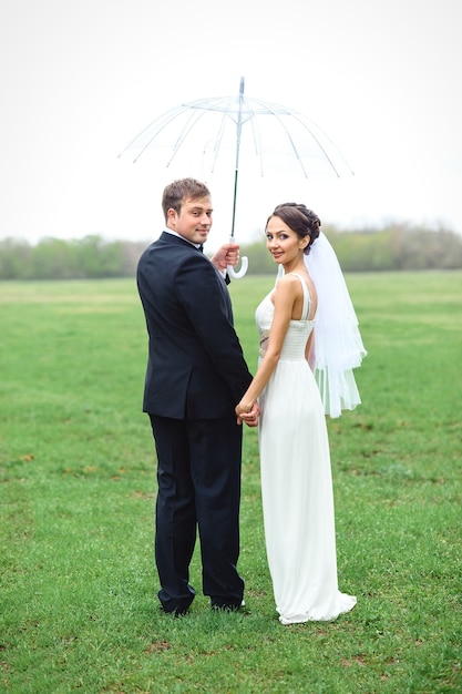 Bride and groom on a rainy wedding day walking under an umbrella