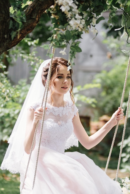 The bride and groom ride a rope swing in the garden. Wedding in the forest.