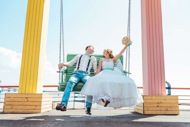 The bride and groom ride on a swing