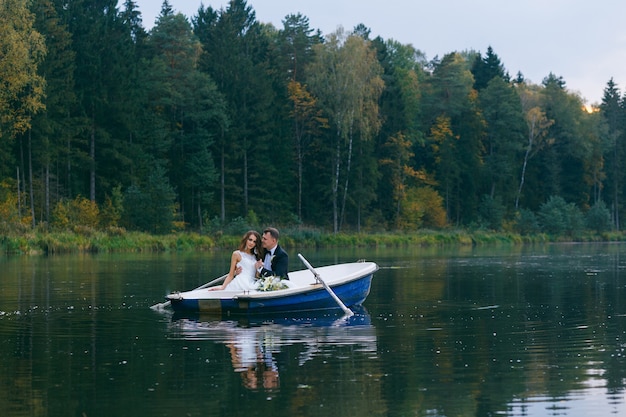 The bride and groom in a rowboat on the lake at sunset