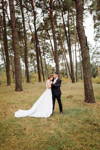 Foto gli sposi corrono attraverso una foresta servizio fotografico di matrimonio