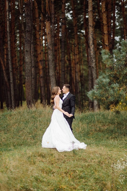 Foto gli sposi corrono attraverso una foresta servizio fotografico di matrimonio