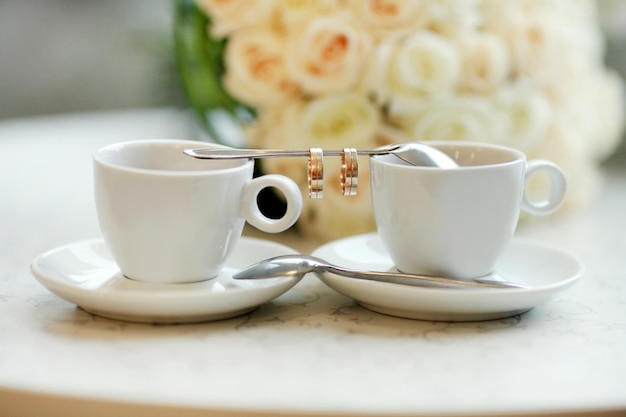 Pausa caffè all'ora del caffè della sposa e dello sposotazze e anelli su un cucchiaino